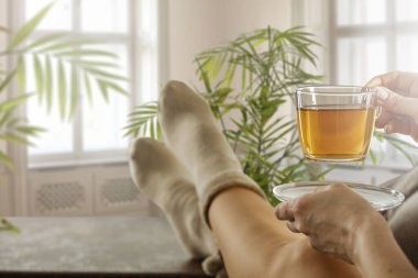 Bacaklar masanın üzerinde çoraplar ve bahar güneşi pencerenin dışında.