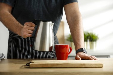 Bir erkek el çay ve mutfak arkaplanı yapıyor.