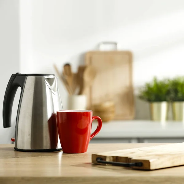 Electric kettle and a red mug on the kitchen table