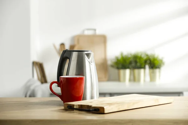 Electric kettle and a red mug on the kitchen table