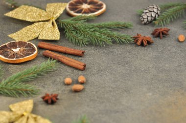 Metin yerleştirmek için Noel kompozisyonu. Badem, anason, çam kozalağı, ladin dalı, turuncu, altın yay, koyu arkaplanda tarçın çubukları. Yakın plan..