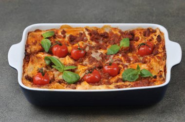 Kiraz domatesli lazanya ve taze fesleğen yaprağı. Yakın plan. Koyu arkaplan.