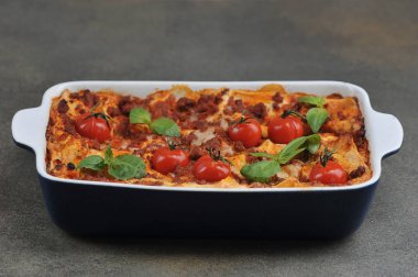 Kiraz domatesli lazanya ve taze fesleğen yaprağı. Yakın plan. Koyu arkaplan.