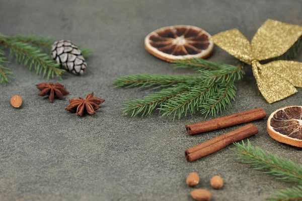Metin yerleştirmek için Noel kompozisyonu. Badem, anason, çam kozalağı, ladin dalı, turuncu, altın yay, koyu arkaplanda tarçın çubukları. Yakın plan..