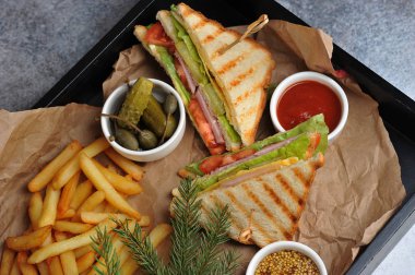 Jambonlu sandviç, peynir, kızarmış ekmek üzerine sebze. Patates kızartması, hardal ve ketçap klasik kulüp sandviçini tamamlar. Yukarıdan bak. Makro çekim.