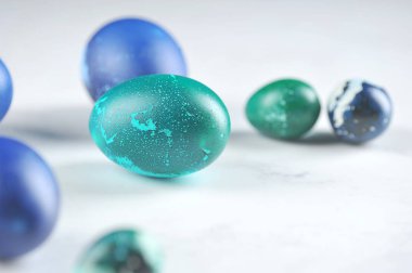 Yeşil ve mavi renkli Paskalya yumurtaları açık arkaplanda. Yakın plan. Makro atış. Metin için boş alan.