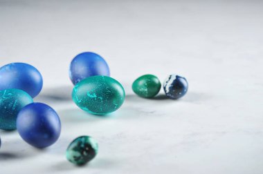 Yeşil ve mavi renkli Paskalya yumurtaları açık arkaplanda. Metin için boş alan.