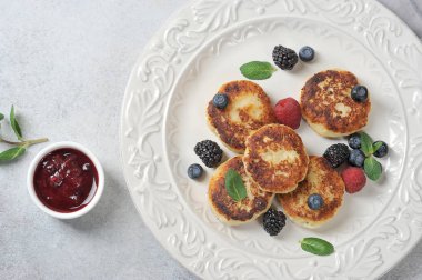 Böğürtlenli peynirli kek. Peynirli kekler taze böğürtlen, böğürtlen, yabanmersini ve nane ile servis edilir. Hafif arkaplan. Yukarıdan bak. Yakın plan..