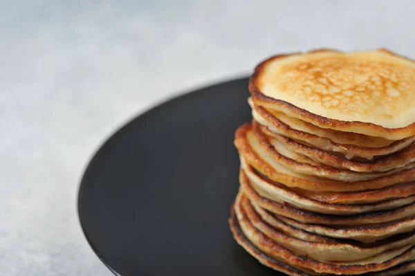 Pancakes on a black plate. Pancakes without additives. Close-up. Free space for text.