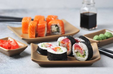 Ton balığı, avokado, Philadelphia peyniri, taze salatalık. Arka planda soya sosu, zencefil ve wasabi turşusu. Hafif arkaplan. Yakın plan..