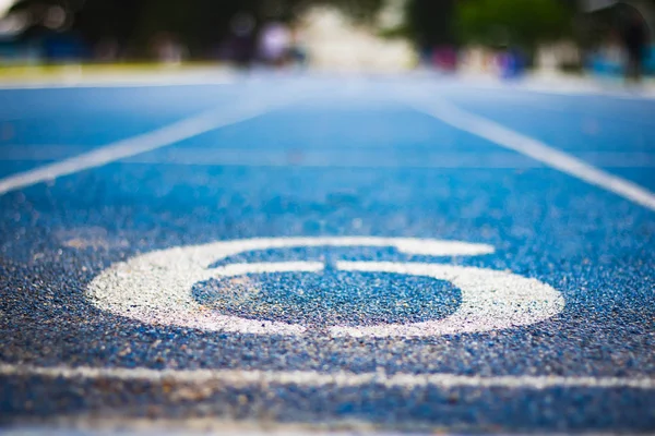 Koşu yolunun başlangıcında altı numara. Farklı numaralar ve beyaz çizgilerle mavi koşu bandı. Seçmeli olarak Numara 'ya odaklan. Arkaplan mavisi. Kapat.