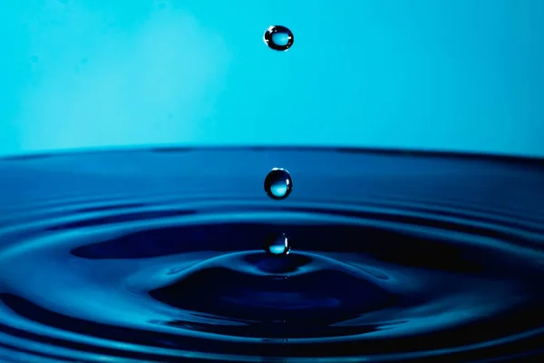 Water Druppel Plons Een Glazen Beker Blauw Gekleurd — Stockfoto