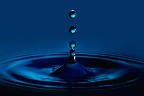 Water Druppel Plons Een Glazen Beker Blauw Gekleurd — Stockfoto