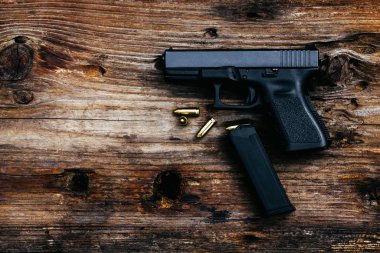 Eski ahşap arka planda cephanesi olan 9 mm 'lik bir silah. en üstteki görünüm