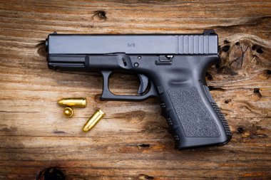 Eski ahşap arka planda cephanesi olan 9 mm 'lik bir silah. en üstteki görünüm