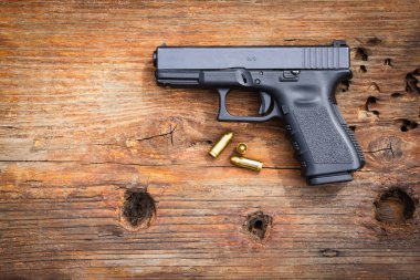 Gun with ammunition on old wooden background. top view
