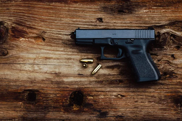 Gun with ammunition on old wooden background. top view