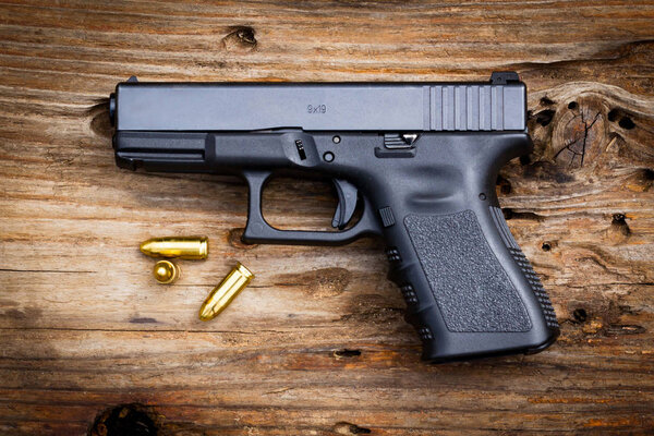 9 mm pistol Gun with ammunition on old wooden background. top view