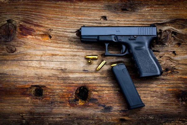 Eski ahşap arka planda cephanesi olan 9 mm 'lik bir silah. en üstteki görünüm