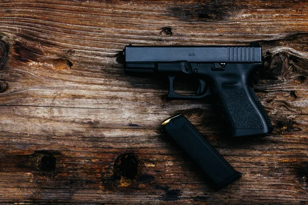 Eski ahşap arka planda cephanesi olan 9 mm 'lik bir silah. en üstteki görünüm