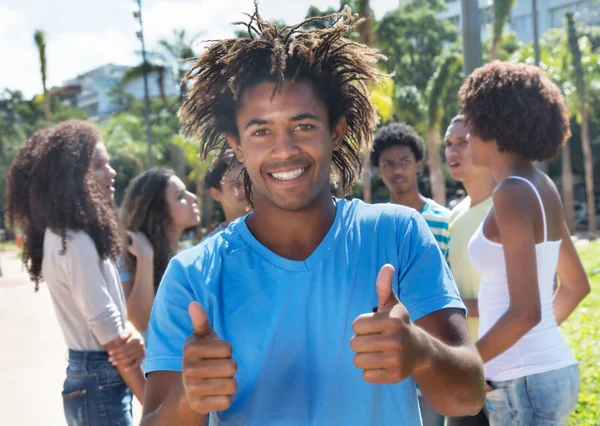 Laughing colombian guy showing thumbs with friends — Stock Photo, Image