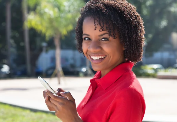 携帯電話でメッセージを送信するアフリカ系アメリカ人の女性は笑ってください。 — ストック写真