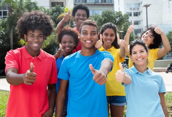 Group of happy multiethnic young adults showing thumbs — Stock Photo, Image