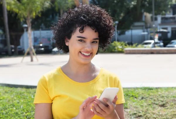 Молодая белая женщина с вьющимися волосами отправляет сообщение с мобилем — стоковое фото