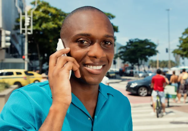 Homem africano feliz usando celular em um olhar de cinema quente — Fotografia de Stock