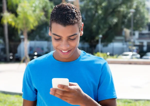 Young latin american hipster sending message by phone outdoor — Φωτογραφία Αρχείου