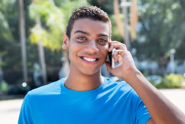 Young latin american man laughing at phone outdoor — Stockfoto