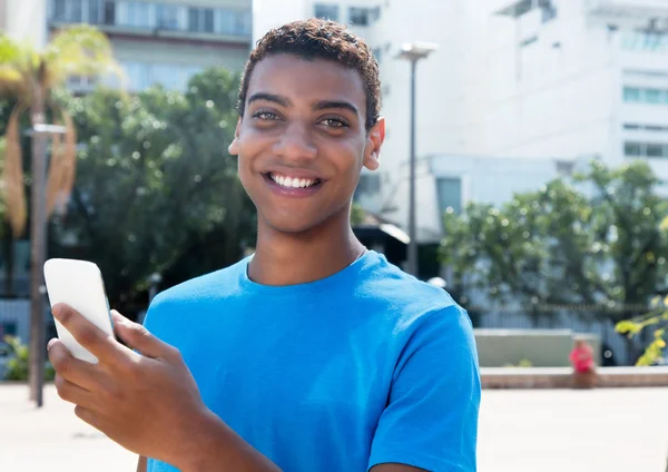 Молодой латиноамериканец-хипстер, пользующийся интернетом по телефону — стоковое фото