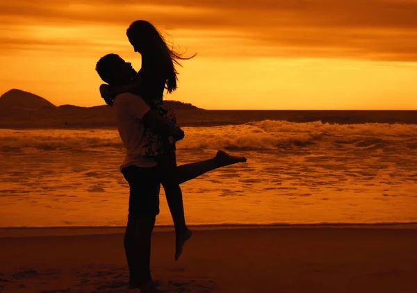 Silhueta de feliz jovem amor casal abraçando na praia no por do sol — Fotografia de Stock