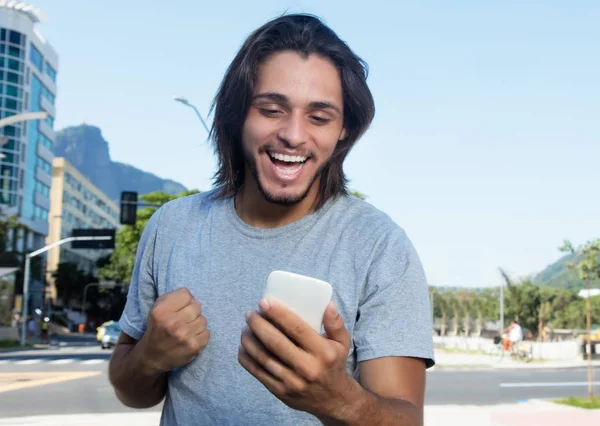 Hipster with long brunette hair receiving good news on phone — Stock Photo, Image