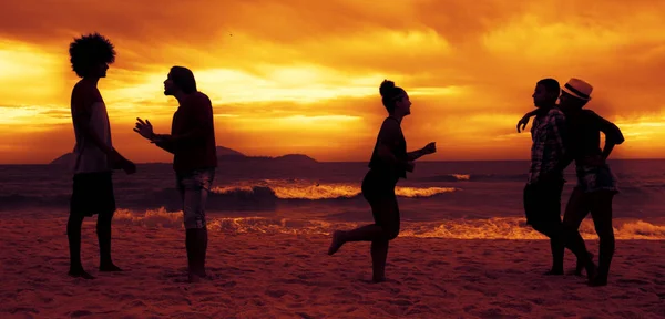 Pareja y amigos y corredor en la playa al atardecer —  Fotos de Stock