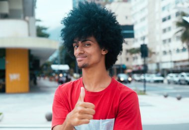 Başparmak gösterilen tipik afro saçlı Afrika kökenli Amerikalı adam