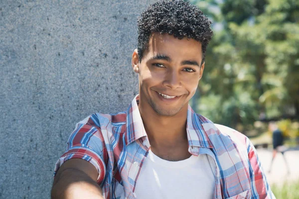 Feliz adulto joven latino en el parque mirando a la cámara — Foto de Stock