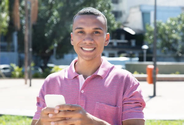 Riendo joven mexicano hombre mensajería por teléfono —  Fotos de Stock