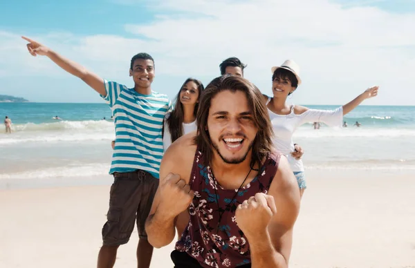 Riendo hombre caucásico con animar a los adultos jóvenes en la playa — Foto de Stock