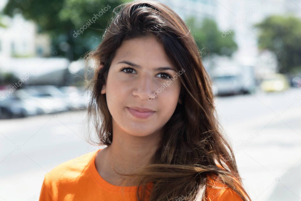 Smiling caucasian woman in a orange shirt in the city