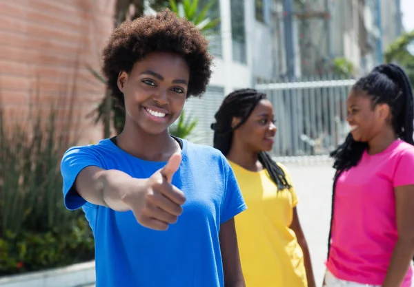 Prachtige Afrikaanse Amerikaanse vrouw toont duim met andere meisjes — Stockfoto