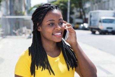 Cep telefonu, sarı gömlekli şirin Afrikalı-Amerikalı kadın