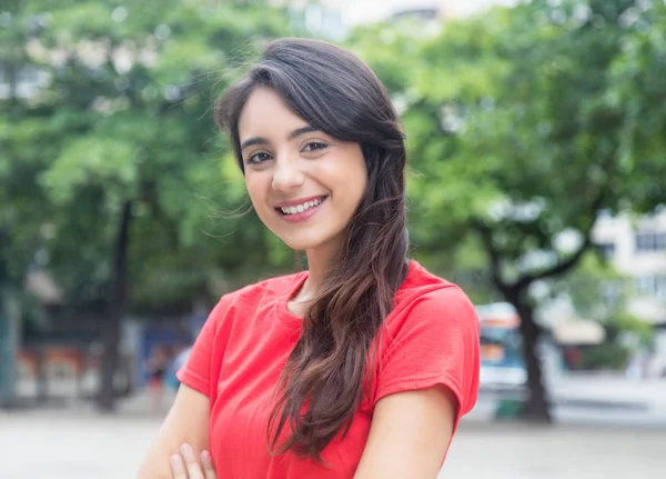 Leuke jonge vrouw in een rood shirt kijken camera buiten in een p — Stockfoto