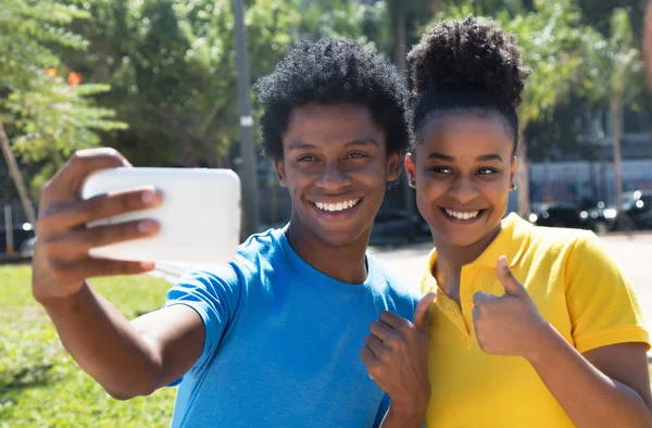 Joven afroamericano hombre con latina mujer tomando selfie con p —  Fotos de Stock