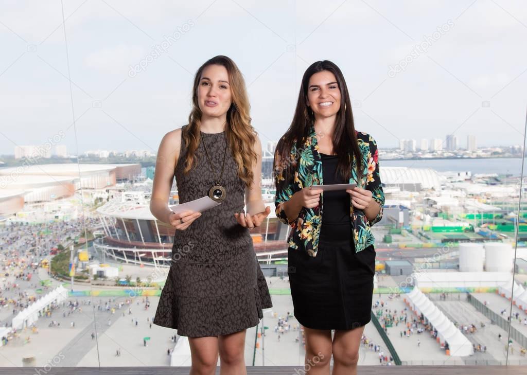 Latin female presenter and caucasian woman looking at television