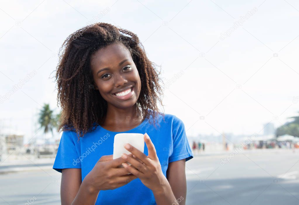 African american woman sending message with phone