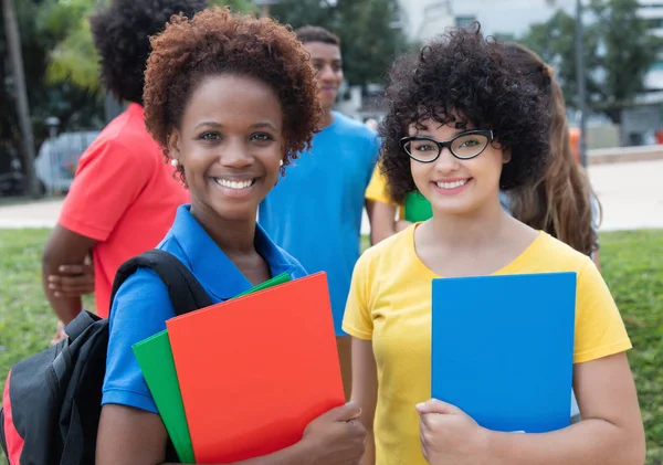 African american och kaukasiska kvinnlig student med grupp av mult — Stockfoto