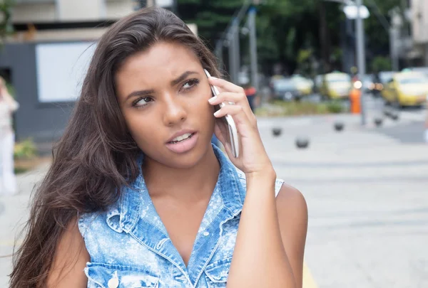 Pensant femme latino-américaine en jean veste au téléphone — Photo