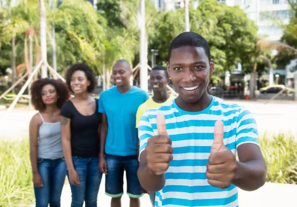 Afro-Amerikaanse man tonen duim met groep mensen lachen — Stockfoto