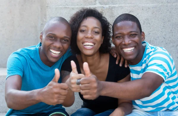 親指の 3 つのアフリカ系アメリカ人の男性と女性を示す — ストック写真